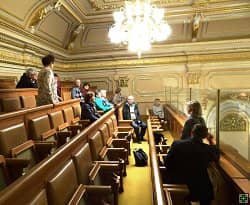 Skupina lidí v historickém sále s křesly a lustrem