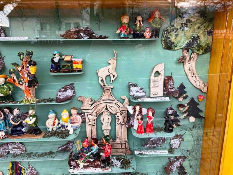 Keramické figurky a předměty v dřevěné vitríně