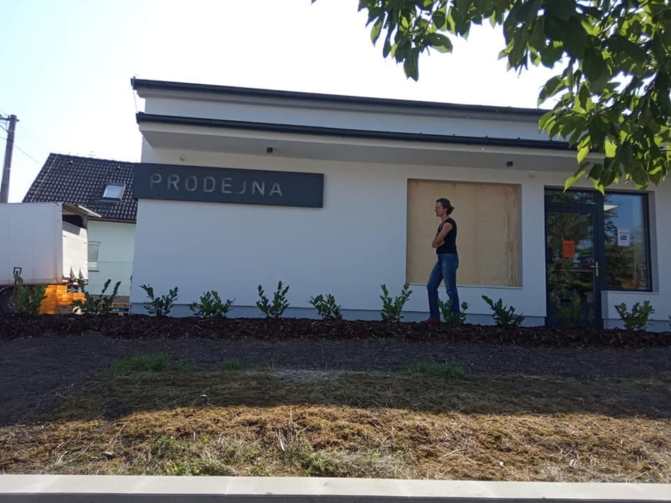 Žena stojí před budovou s nápisem PRODEJNA