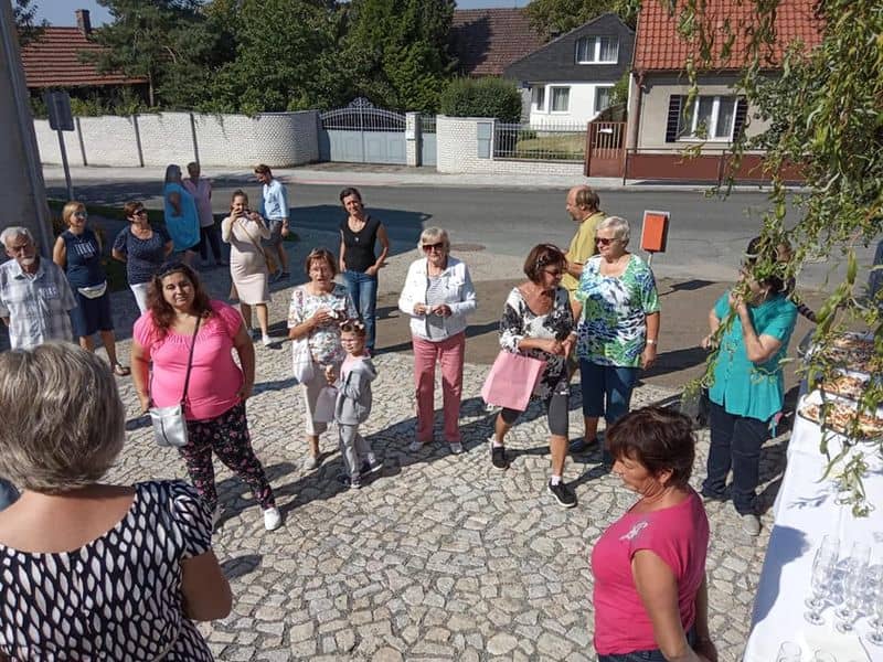 Skupina lidí na dlážděné cestě před domy