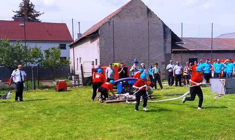 Děti v hasičských uniformách při soutěži v požárním útoku