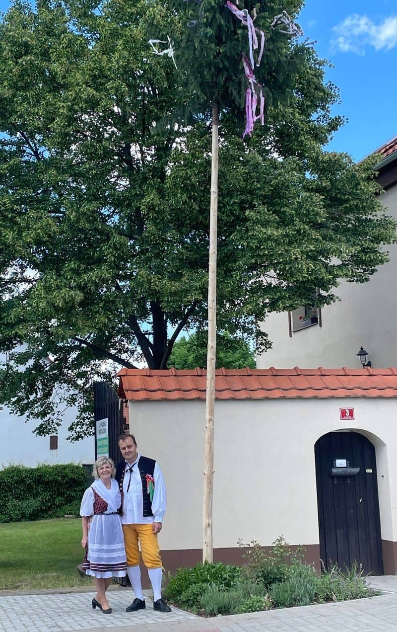 Pár v krojích stojí u májky před domem