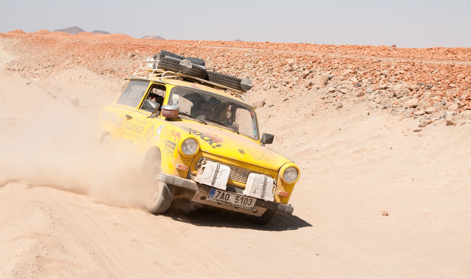 Žlutý Trabant na prašné cestě v poušti