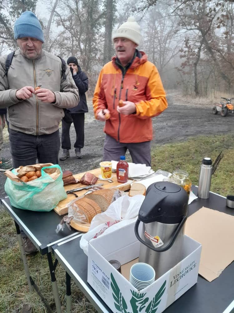 Skupina lidí u stolu s jídlem a pitím v mlhavém lese