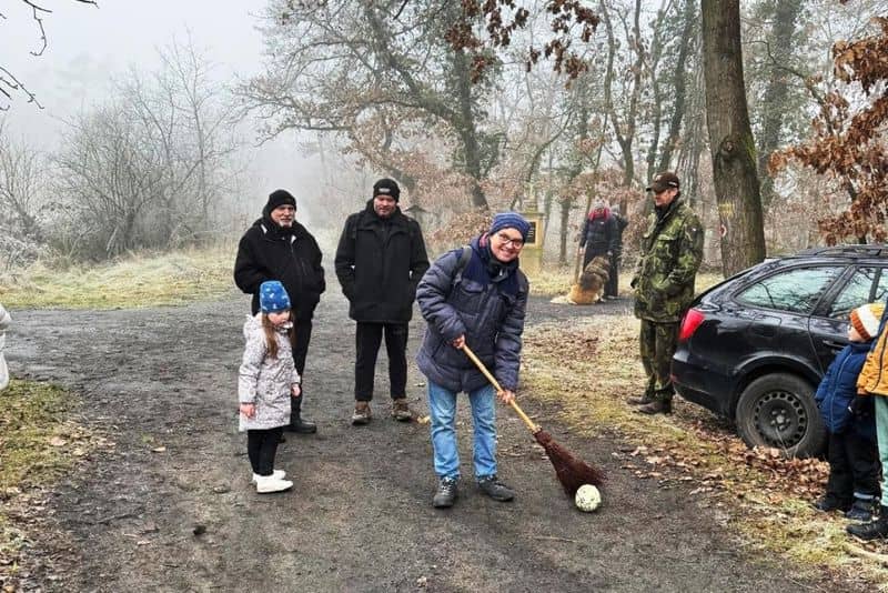 Skupina lidí s dětmi hraje hru s koštětem a míčem v lese