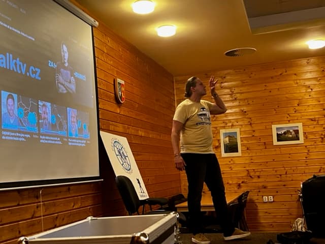 Muž přednáší u promítacího plátna s webovou stránkou
