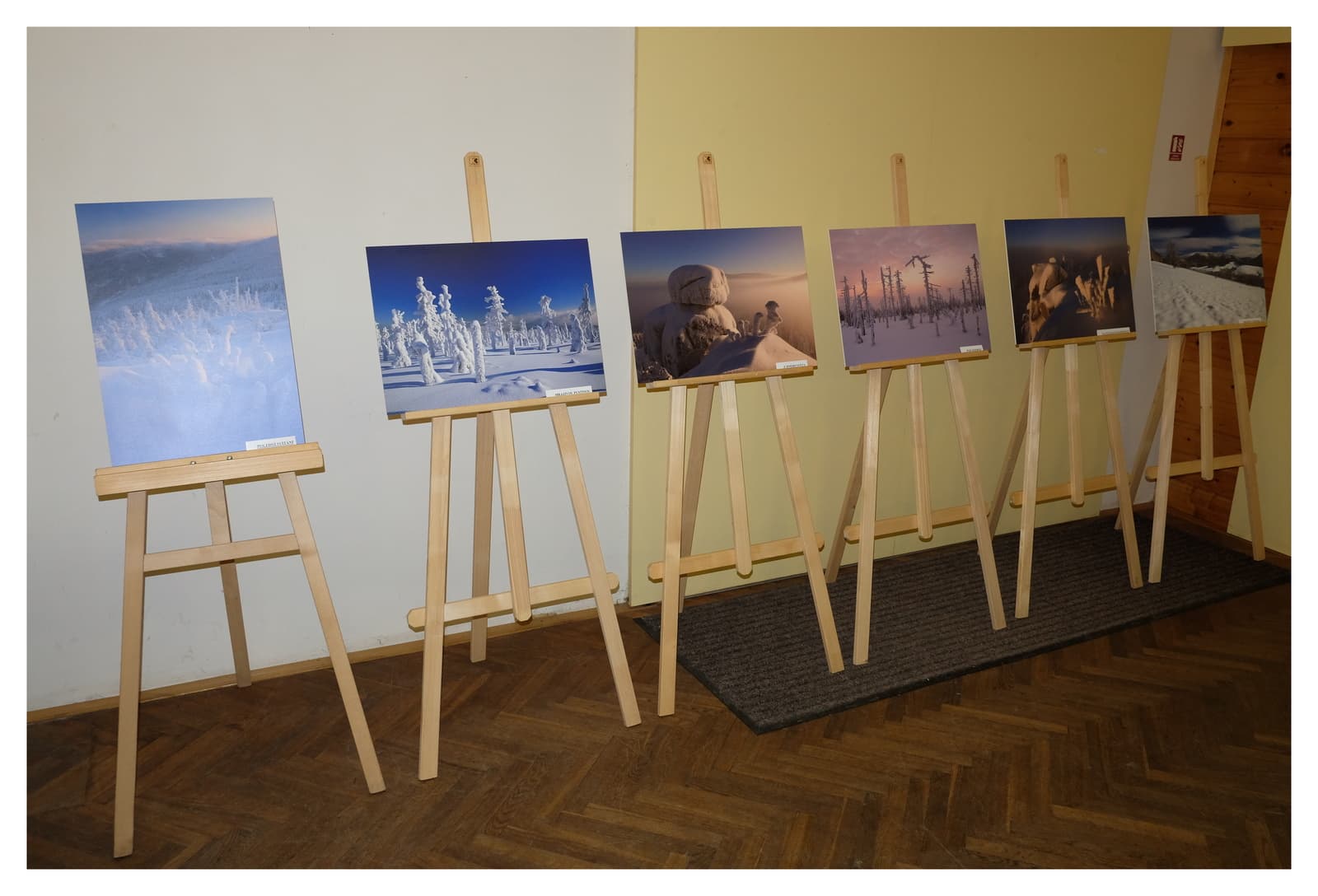 Výstava fotografií zimní krajiny na dřevěných stojanech