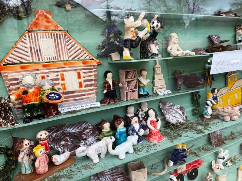 Keramické figurky a domečky vystavené v polici