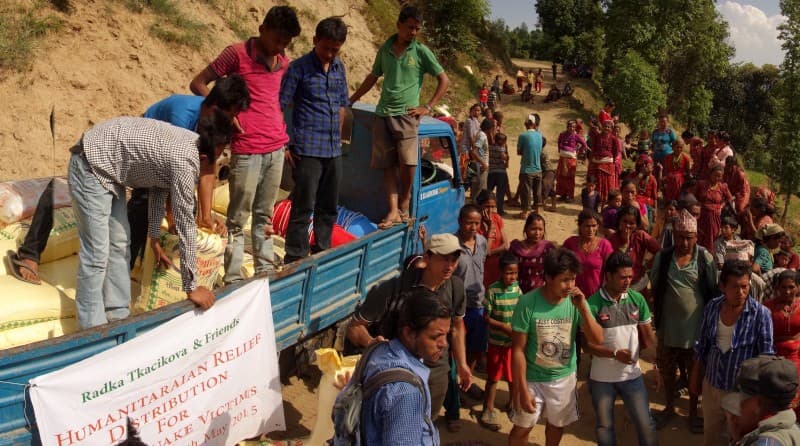 Lidé vykládají humanitární pomoc z nákladního auta, v pozadí dav lidí