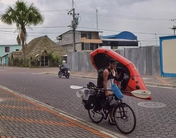 Muž s kolem a nafukovacím kajakem na ulici