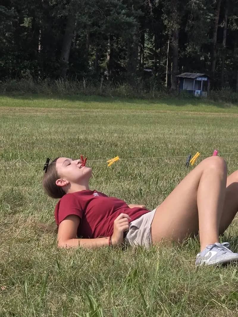 Účastnice tábora odpočívá vleže na trávě.
