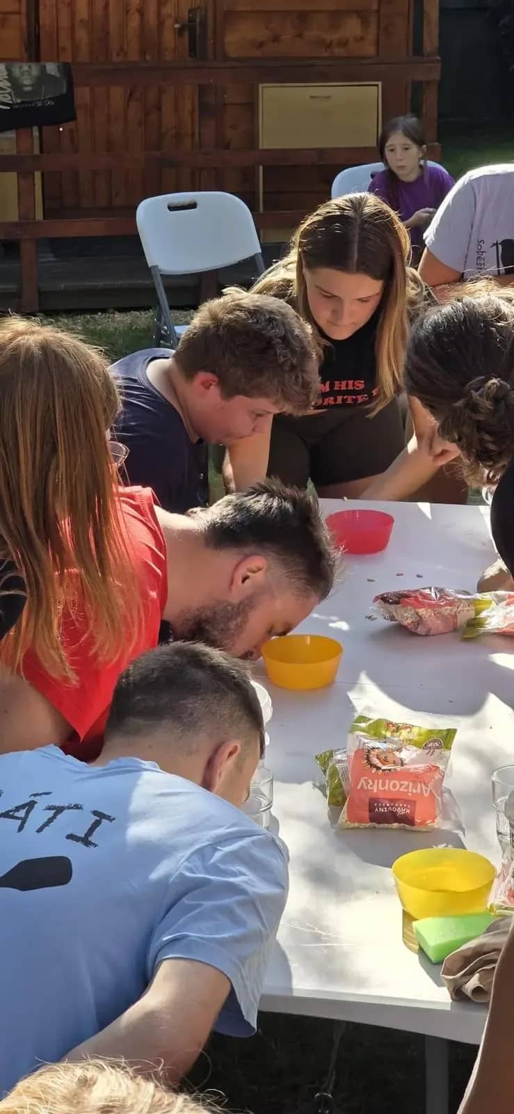 Skupina dětí pracuje s potravinami u venkovního stolu.