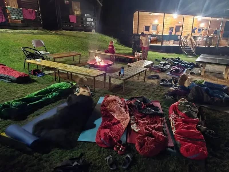 Spací pytle a karimatky rozložené venku u stolního tenisu.