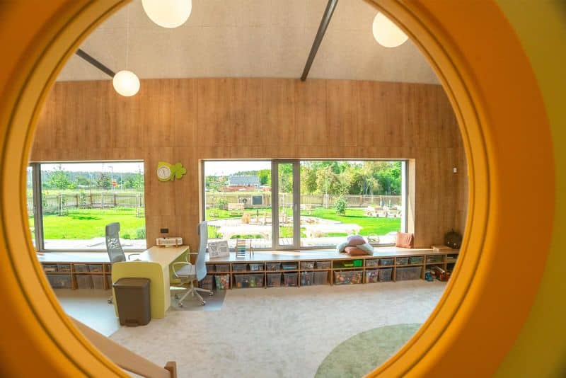 Interiér moderní školky s velkými okny a výhledem na zahradu