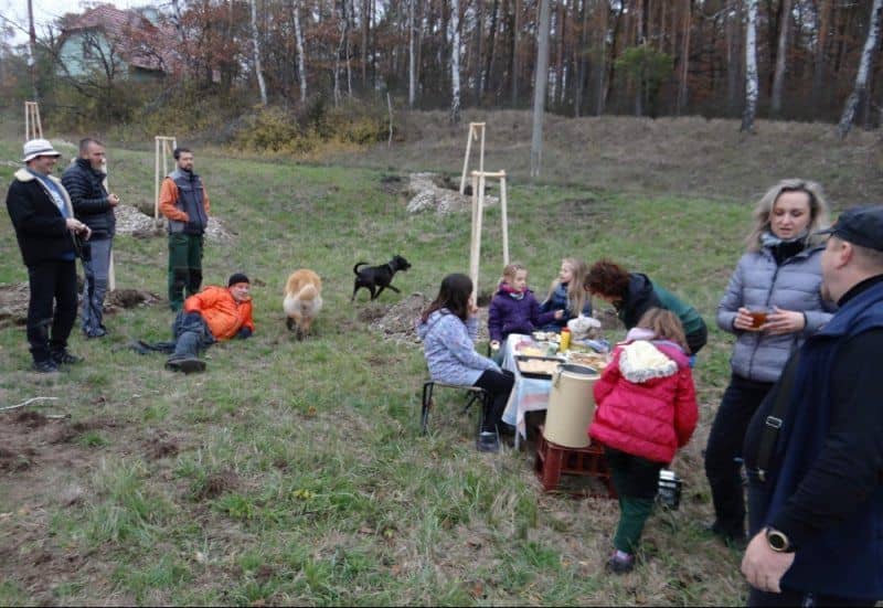 Skupina lidí a děti s psy u stolu s občerstvením v přírodě