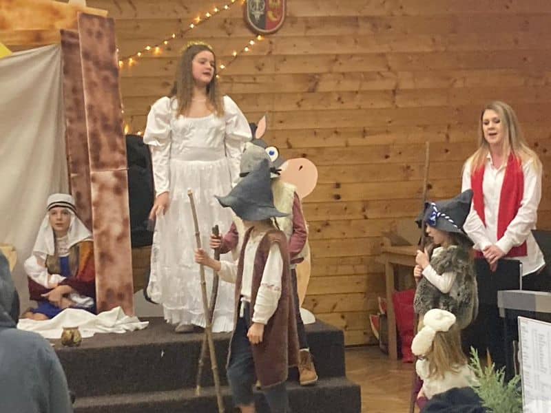 Děti a dospělí v kostýmech hrají divadlo na pódiu