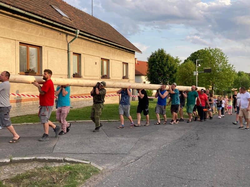 Skupina mužů nese dlouhou kládu po ulici