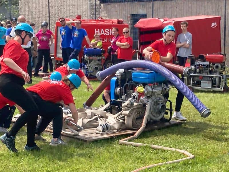 Hasiči při požárním útoku s hadicemi a stříkačkami