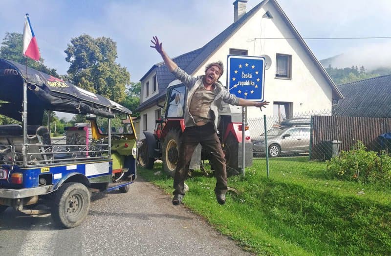 Muž skáče radostí u cedule Česká republika, vedle tuk-tuku s českou vlajkou