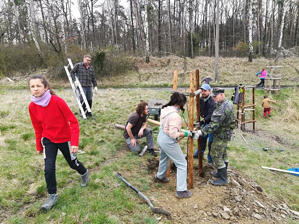 Skupina lidí a dětí pracuje na stavbě v přírodě