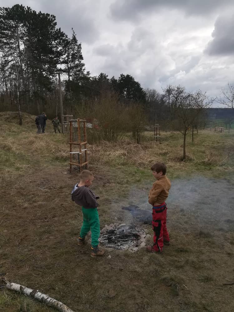 Dva chlapci stojí u ohniště v přírodě
