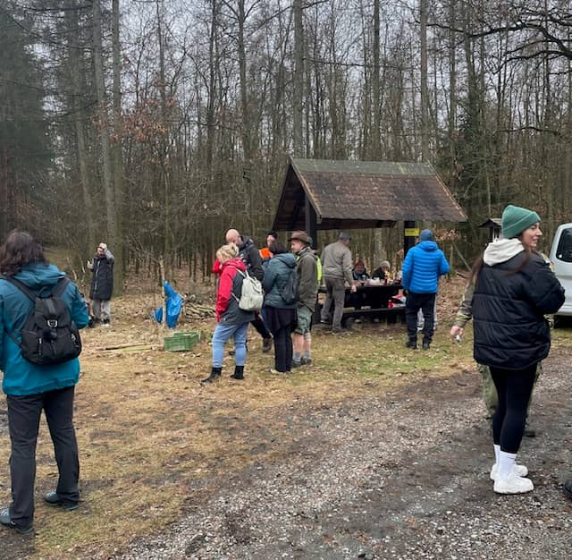 Skupina lidí v lese u dřevěného přístřešku