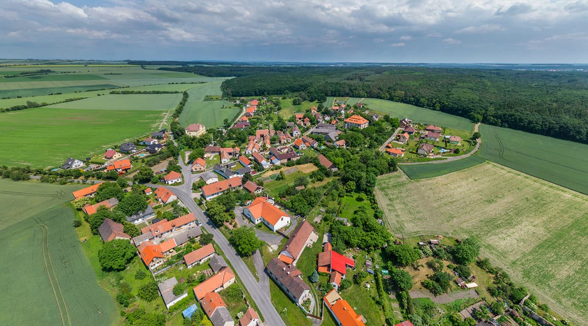 Letecký pohled na Hlavenec obklopený poli a lesem