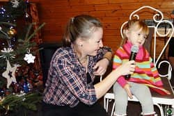 Žena s mikrofonem a malá holčička u vánočního stromku