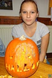 Dívka s vyřezávanou dýní s nápisem HALLOWEEN