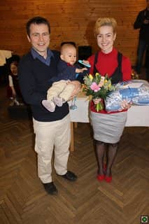Rodina s miminkem, žena drží kytici a balíček