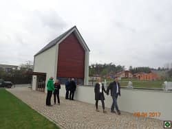 Skupina lidí u moderního domu s dřevěným obložením