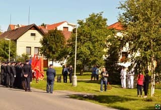Skupina lidí v uniformách s vlajkami na ulici