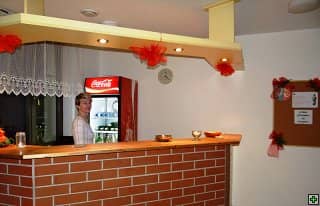 Žena za barem s cihlovou zídkou a lednicí Coca-Cola