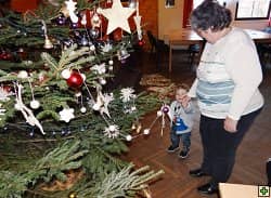 Žena s malým dítětem u ozdobeného vánočního stromku