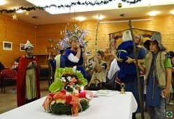Děti a dospělí v kostýmech u stolu s adventním věncem
