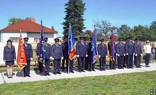 Skupina hasičů v uniformách s prapory