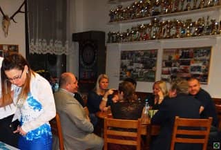 Skupina lidí sedí u stolu v místnosti s trofejemi na stěně