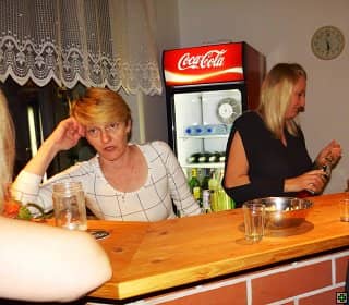 Dvě ženy za barem, jedna se opírá o ruku, druhá nalévá pití