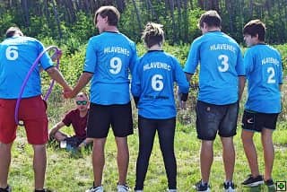 Pět mladých lidí v modrých dresech s nápisem HLAVENEC, jeden sedí v trávě