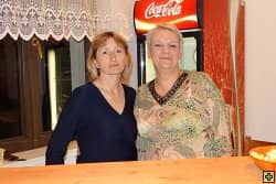 Dvě ženy stojí za pultem, v pozadí lednice Coca-Cola