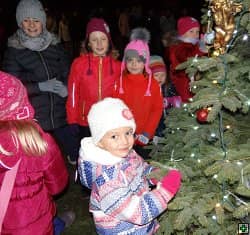 Děti u vánočního stromku s ozdobami a světýlky