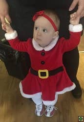Dítě v kostýmu Santa Clause držené za ruce