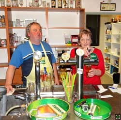 Muž a žena za barem, žena čepuje pivo