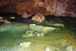 Jeskynní jezero s kameny a kruhy na hladině