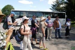 Skupina lidí vystupuje z autobusu na parkovišti