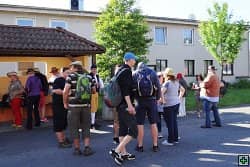 Skupina lidí před budovou, někteří s batohy