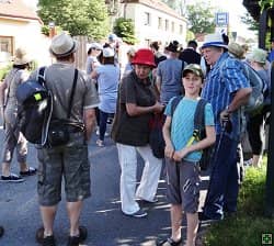 Skupina lidí s klobouky na ulici, v pozadí autobusová zastávka