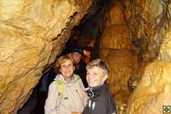 Tři lidé v jeskyni se stalagmity a stalaktity
