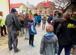 Skupina dospělých a dětí na cestě před starým domem