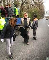 Skupina lidí uklízí odpadky u silnice
